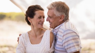older couple man woman smiling and embracing outdoors blurred background
