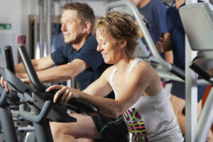 man and woman exercising at gym on cycles