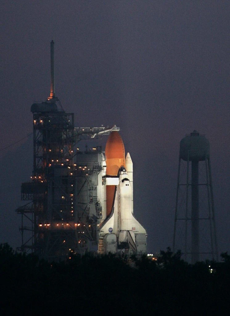 space shuttle discovery lit up on launch pad at night
