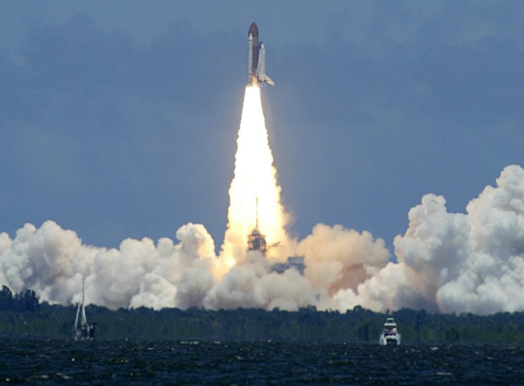 space shuttle discovery moments after takeoff rocket plume and clouds