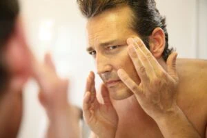 Skin care older man in mirror