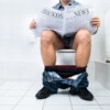 Close-up,Of,A,Man,Sitting,On,Commode,Reading,Newspaper