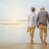 Senior,Couple,Walking,On,The,Beach,Holding,Hands,At,Sunrise,