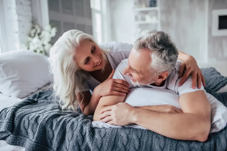 Senior with backpain and partner lying on a bed